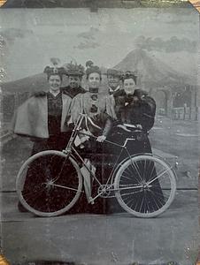 Group of people including Ruth Simpkins and Mabel Simpkins with a bicycle