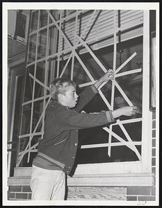 Taped Windows were a common sight along Main street in Wareham last night as it prepared for Hurricane Esther. Here, Robert Voss, 14, of Swift's Beach helps safeguard window of barber shop.