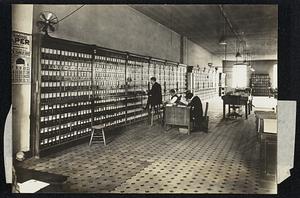 Scene in the Identity Bureau. Each of the little pigeon holes in the cabinet along the wall contains from fifteen to twenty records. Every record furnishes an absolute and indisputable proof of the identity of the man who made the imprint. There are more than 5,000,000 (5,000) records in the bureau.