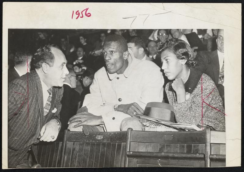 Bill Russell Watches his New Teammates during game in New York. With him are coach Red Auerbach of the Celtics and Mrs. Russell. It was the first time Russell ever had attended a pro basketball game.