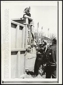 An unidentified demonstrator is assisted down from his perch by a Denver police officer. Denver Police moved onto the Denver University campus early Monday morning to evict 1,000 students from a makeshift village set up near the Student Union Building. There was no violence. Twenty-eight students were arrested.