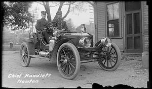 Two Firemen on Antique Fire Department vehicle, one identified at Chief Randlett