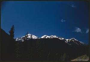 View of snow-capped mountaintops above shadowed hills, British Columbia