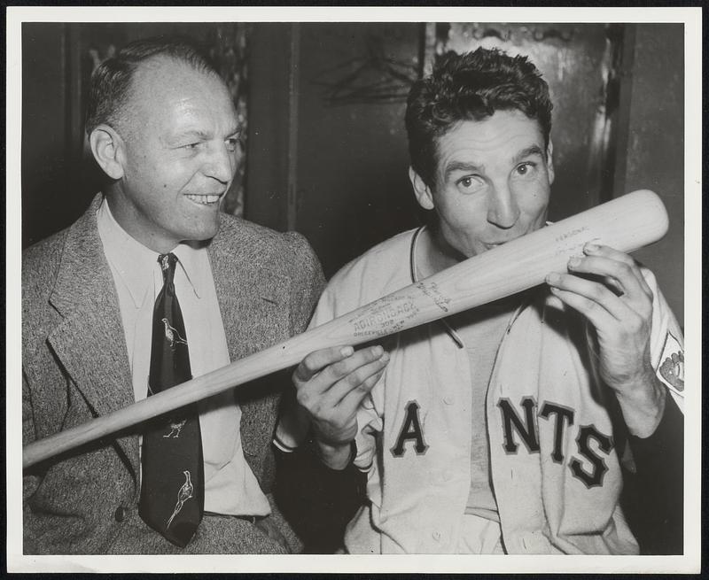 Bobby Thomson smacks the bat grown in New York State's Adirondacks with which he banged out the sensational homer when the Giants beat out Brooklyn in the exciting 1951 National League pennant race. Hal Schumacher, former Giant pitching star, look on.