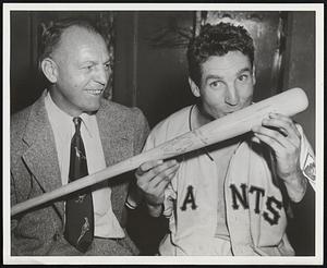 Bobby Thomson smacks the bat grown in New York State's Adirondacks with which he banged out the sensational homer when the Giants beat out Brooklyn in the exciting 1951 National League pennant race. Hal Schumacher, former Giant pitching star, look on.