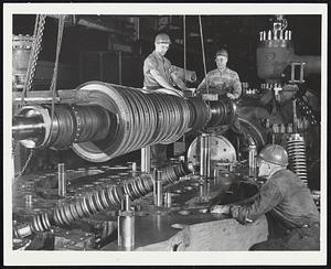 Factory tests for the world’s first commercial supercritical pressure steam turbine-generator unit have begun at General Electric Company’s Large Steam Turbine-Generator Department plant in Schenectady, N.Y. Workmen are seen above leveling the seven-ton supercritical pressure element turbine rotor prior to lowering it into the turbine shell. The unit will operate at an initial steam pressure of 4500 psig at a temperature of 1150° F. The highest steam pressure used by turbines now in service in the world is 2400 psig. This powermaker is rated at 125,000 kilowatts and is capable of furnishing enough electricity to satisfy the average yearly electrical needs of over 208,000 persons. This steam turbine-generator unit is scheduled for installation this year at the Philo, Ohio, power station of the Ohio Power Company of the American Gas and Electric System.