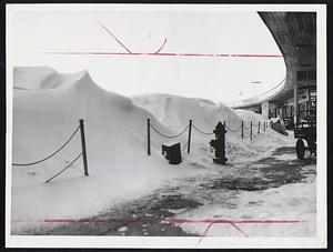 Obstructing Airport View are these wind sculptured snow drifts piled up nearly as high as the promenade roof of the Boston Airport Terminal Building.