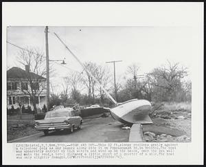 Bristol, R.I. - High And Dry - This 22 ft. slope reclines gently against a telephone pole as car passes along side it on Poppasquash Rd. in Bristol. The boat was apparently carried by high waters and wind up on the beach, over the sea wall and onto the road, a total distance a little short of a quarter of a mile. The boat was only slightly damaged.