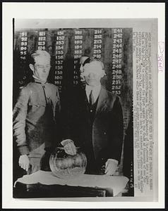 Newton D. Baker, Secretary of War, reaches into a glass bowl on July 20, 1917 to withdraw the first number in the draft of thousands of men for military service. Today, the big dispute about the draft is centered on whether smart college students should be deferred while those of scanter attainments put their lives on the line in Vietnam.