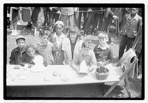 A group of children behind a collection of items