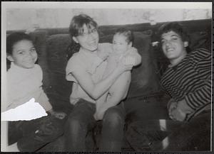Group of young people smiling on a couch, one holding baby Luis