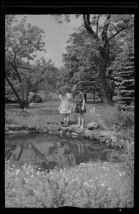Two young girls standing looking in pond