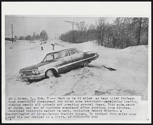 Akron, O. - Gust up to 45 miles an hour piled 10-feet-high snowdrifts throughout the Akron area overnight - paralyzing traffic, closing nearly all schools and creating general chaos. This auto, south of Akron, was one of hundreds abandoned after skidding into ditches. Countless residents walked to work, including Robert Nibert - a meteorologist at Akron-Canton Weather Bureau. He trudged five miles when his car stalled in a drift.