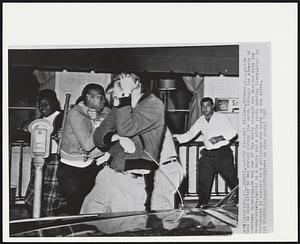 Cover Up – Carl Willmen, Paramus, N.J., holds hand to head after he was struck during the march through the streets of downtown Cambridge. He was one of the white student who marched with the demonstrators. Behind is a negro and a white youth trading blows. Stick in background is wielded by a policeman who broke up the melee.