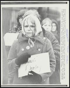 A young girl with wind and rain-swept hair walks past the White House 11/14 as a heavy rain falls during the “March Against Death.” She is carrying a placard with the name of “Dennis Dooley,” an American killed in Vietnam.