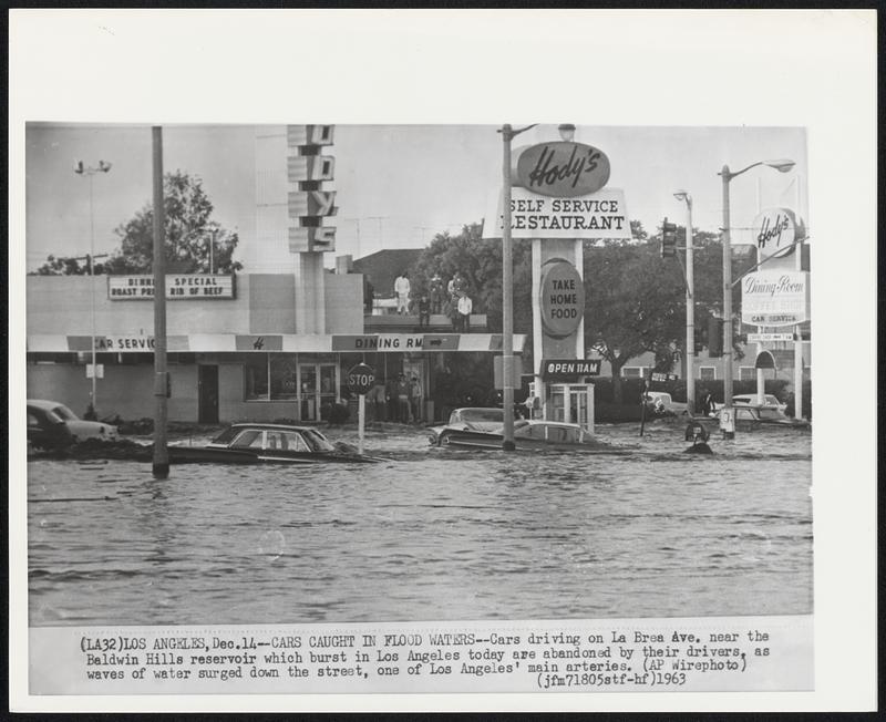 Cars Caught in Flood Waters--Cars driving on La Brea Ave. near the Baldwin Hills reservoir which burst in Los Angeles today are abandoned by their drivers, as waves of water surged down the street, one of Los Angeles' main arteries.