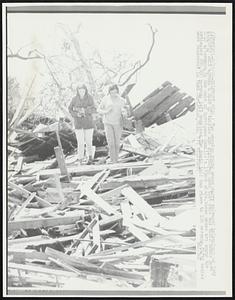 Two weeping young women carry salvaged belongings as they gingerly walk across a mass of twisted and splintered wood that once was their homes here 8/18 afternoon. In the wake of hurricane Camille's 190mph winds, these women are among the estimated 200,000 persons left homeless. The death toll has risen to 106 persons. Fifty bodies were recovered in Pass Christian, Miss.