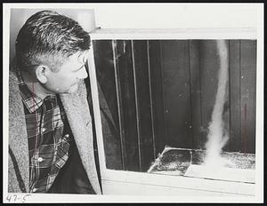 At a "baby" tornado he made in box, is Prof. Fred C. Bates of Kansas University. A vacuum is created with a 12-h.p. motor which sucks air out of the box. Dry ice vapor moves upward in the funnel of air-and the baby tornado is born.