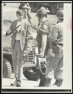 A policeman disarms a youth carrying a pistol at Kent State University campus. Four persons were reported killed and others wounded when National Guardsmen fired into crowd on the commons after anti war demonstrators hurled rocks at them.