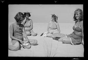 Two women and two girls sitting on sand