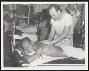 Hawaiian Marathoner Gets Rubdown from Johnny Semple, an old marathoner himself. Norman Tamanaha paid a visit to the effervescent trainer just to make sure there would be no leg-kinks during the B.A.A. Marathon. On another table is Fernie Flaman of the Bruins, getting heat treatment for the leg injured in the National Hockey League playoffs.