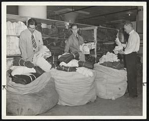 Bales on bales of garments for men, women and children are being packed at the sewing project rooms in the quartermaster warehouses at the Army Base by WPA workers to be shipped to Springfield for flood refugees in that area. These men were busy all day yesterday, while the women of the project sewed busily all day long to meet the demands of the people who have been driven from their homes by floods.