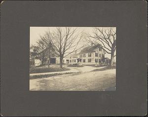 Photograph of the Colburn house and barn from the street, leafless trees in the foreground