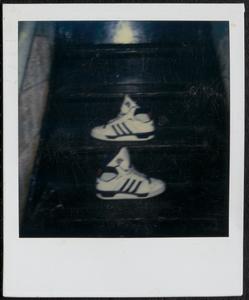 Pair of white and black Adidas shoes on stairs