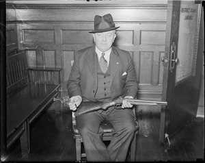 Chief John Cahill of Dedham holding shotgun and revolver used in attempt by Edward Frye to free Millens.