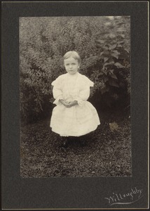 Young child in white dress standing in garden