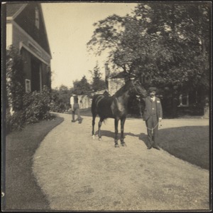 Man with horse in front of barn