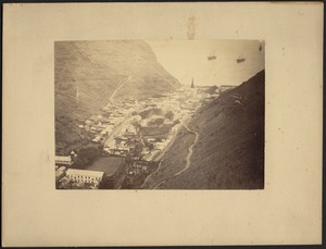 Birds-eye view of village and harbor in mountain valley; three-masted ships in distance