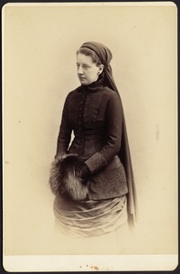 Woman in black dress and headdress holding fur muff, possibly a nurse uniform