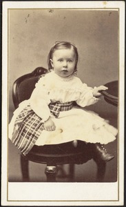 Young child in white frock with woven tartan sash