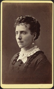 Woman in dark dress with lace collar, braided coiffure, long earrings, brooch