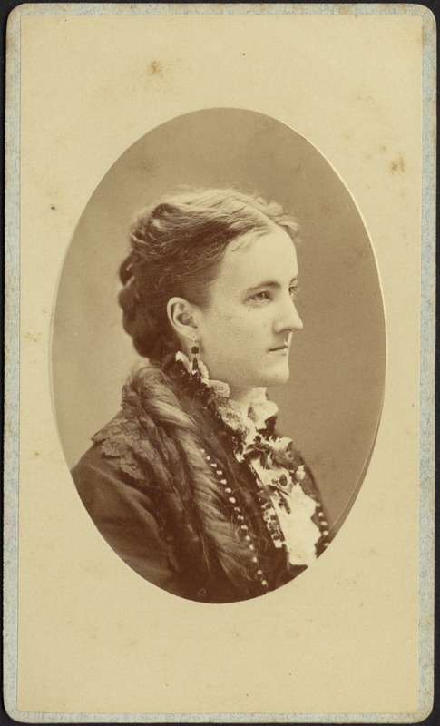 Profile of young woman with long coiffed hair, jet earrings