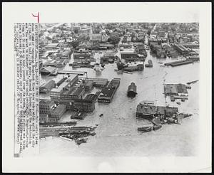 Split in Two by Flood--This aerial view shows flood of rampaging Naugatuck River here today which split the city of 104,000 in half. Its mayor, Raymond E. Snyder said the destruction was “the worst in history” and “just unbelievable. The Naugatuck, racing along at 50 miles an hour, poured over its banks. This picture was taken from a Sikorsky S-58 helicopter, one of scores of both military and civilian ‘copters aiding in disaster relief.