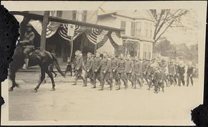 Soldiers parading past flag-decorated buildings