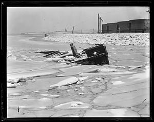 An unidentified item, possibly a boat, sinking in icy body of water