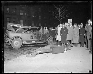 People stand by a wrecked car, broken traffic light in foreground