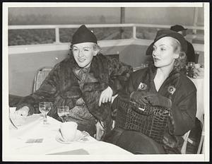 Film Actreses at Race Track Opening. Arcadia, Calif., Dec. 25 - Fashionably Clad Carole Lombard, (right), film star, and Eadie Adams, actress-singer, lunched at The Turf Club, from which they watched the races at the Christmas day opening of Santa Anita meeting.