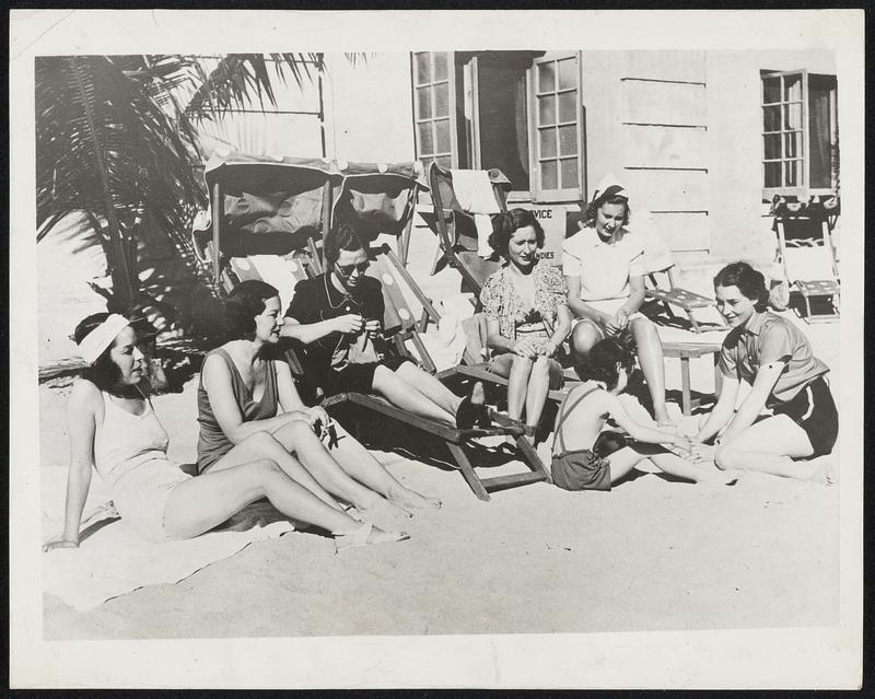 Golf Widows. The above group of ladies belong to that lonesome set known as the “golf widows” during the seasons when their husbands follow the sun in their quest for tournament prizes. From left, they are: Mrs. Paul Runyan; Mrs. Jimmy Thomson, the former Viola Dana of the screen: Mrs. Ralph Hutchinson; Mrs. Frank Walsh; Mrs. Lawson Little, and Mrs. Denny Shute who is helping daughter Nancy build a sand hill.