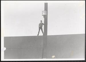 Jimmy Driscoll standing and holding onto a pole