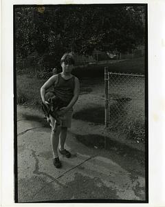 Boy holding a dog on a sidewalk