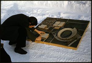 Man examining architectural model on snow-covered ground, Cambridge, Massachusetts