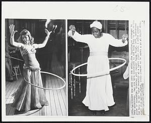 Egypt Now Gets Into The Whirl--The Egyptian, no stranger to body gyrations, has now been introduced to the hula hoop to add to his store of knowledge. Oriental girl dancer Nagwa Fouad, left, introduced the hoop in her dance recently at a Cairo night club. A white gowned night club waiter, right, looks pleased as he makes a go at it.