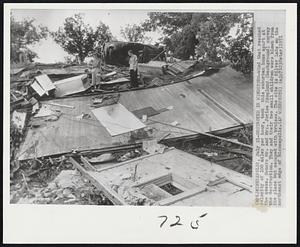 Destroyed in Windstorm-Wind that reached velocity of 100 miles per hour, took this suburban home apart at the seams. Owners Mr. and Mrs. Jorice Skoglund (background) survey the destruction. They and their two small children were blown from the place but escaped with bruises. The site is Silver Lake on the northeast edge of Minneapolis.