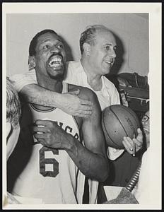 Bill Russell is hugged from behind by a man holding a cigar and a basketball