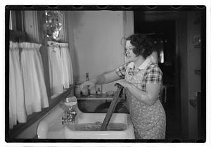 A woman doing laundry at a sink with a washboard