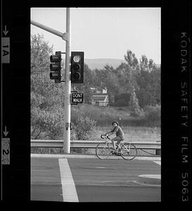 Boy waits on bicycle at street light